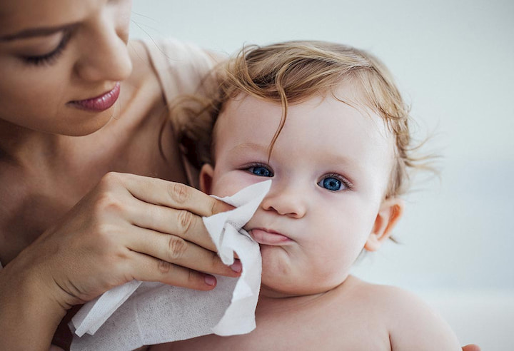 mum cleaning her baby's face with wet wipe