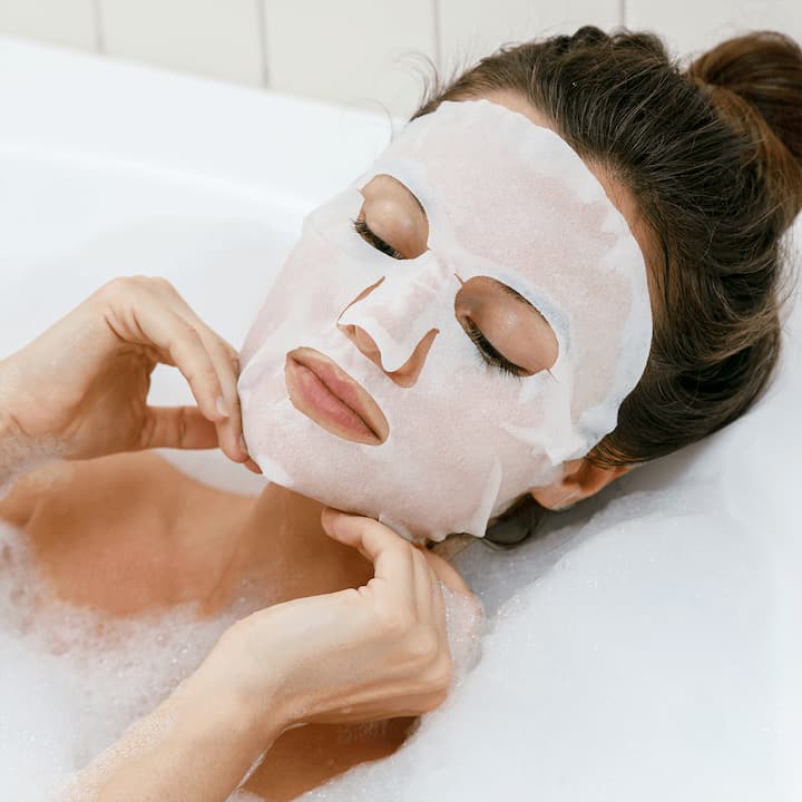 girl having a bath and a sheet mask on her face