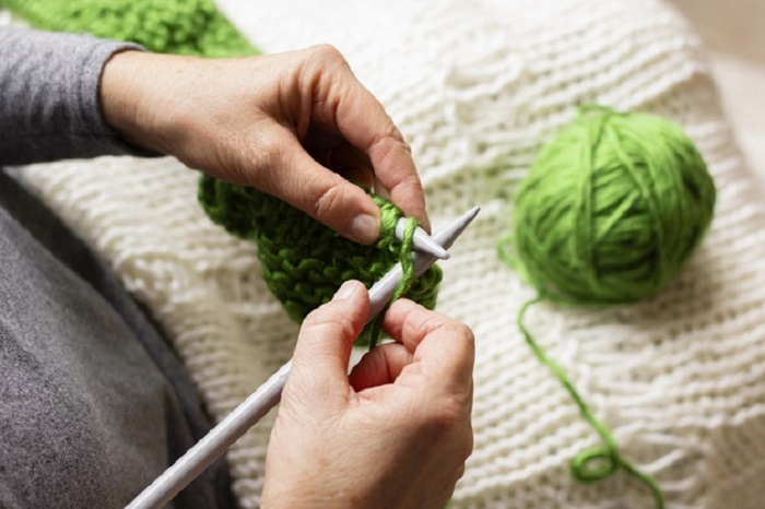 high-view-person-knitting-with-green-thread