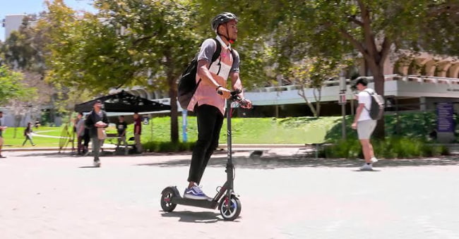 young man riding an electric scooter in australia