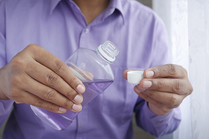 picture of a person in blue shirt holding a mouthwash in his hands