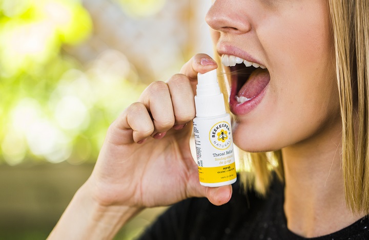 picture of a person applying a propolis spray in her mouth