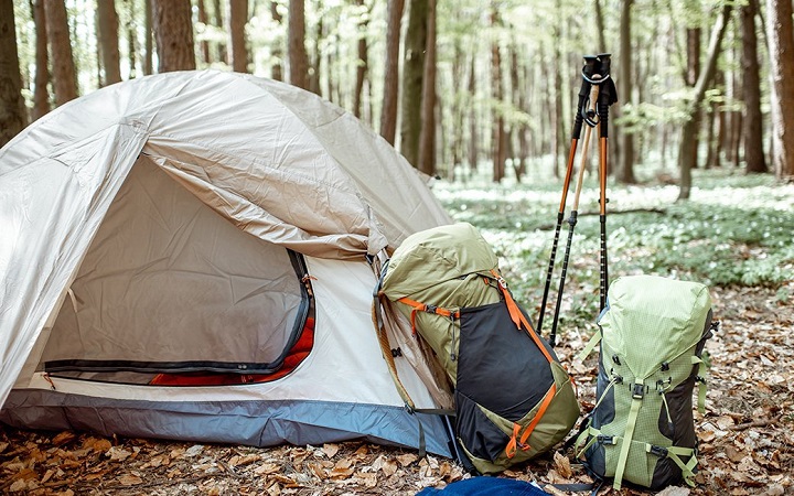 close-up of hiking tent, with backpacks and hiking sticks on the side