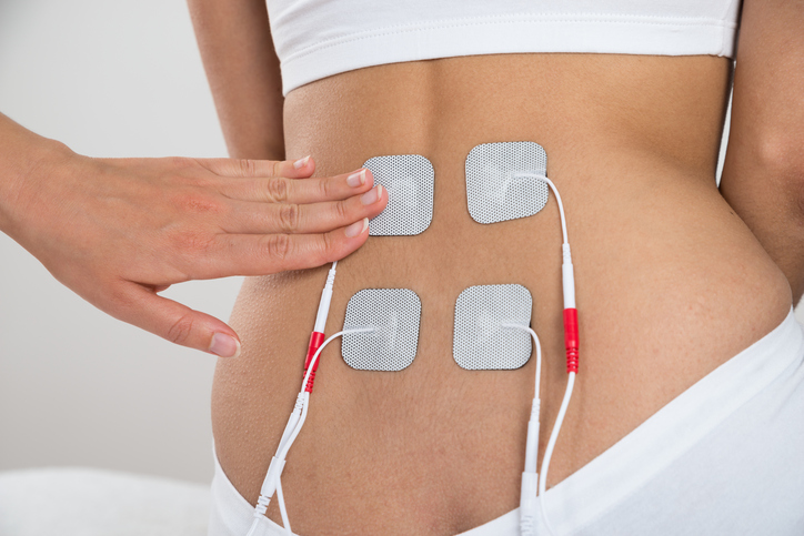 Close-up Of Therapist Placing Electrodes On Woman's Back