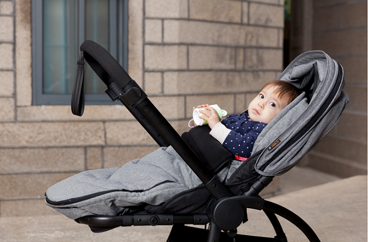 picture of a baby in a pram outside in front a building 
