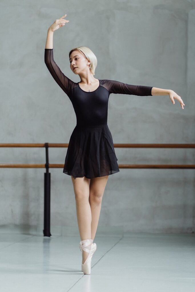 picture of ballerina dancing in a studio wearing long sleeve leotard and ballet shoes 