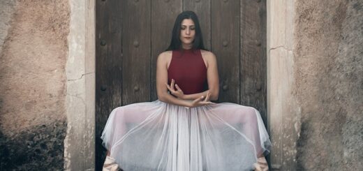 picture of woman dancing ballet in front an old building wearing red basic leotard and a long skirt