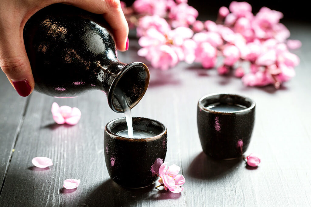 pouring a glass of sake with pink flowers all over the table