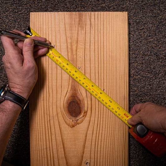 A man working with tape measure on wood