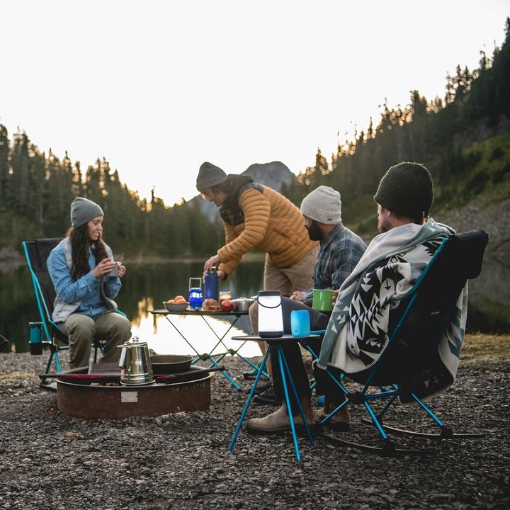 picture of a persons sitting on a folding chairs while camping 