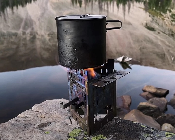 Firebox stove with fire and pot on it in nature