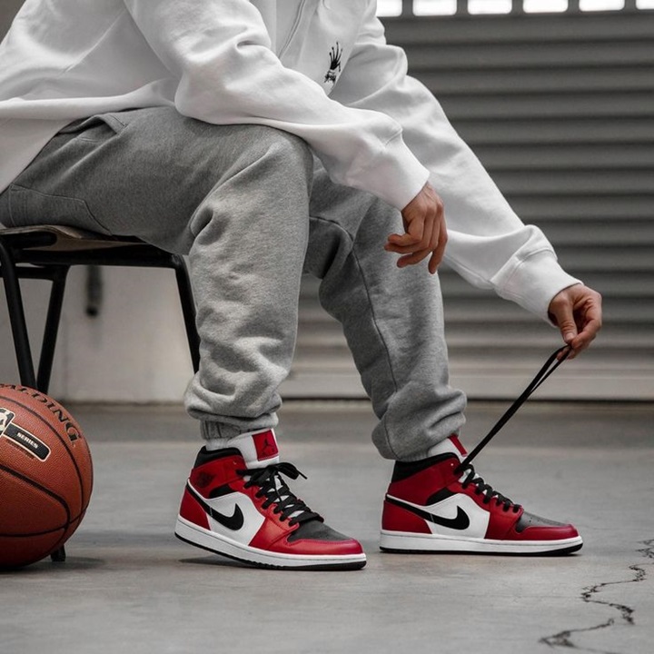 basketball player trying up his nike air jordan 1 sneakers with a basketball next to him
