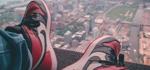 man sitting at the top of a skyscraper with air jordans on