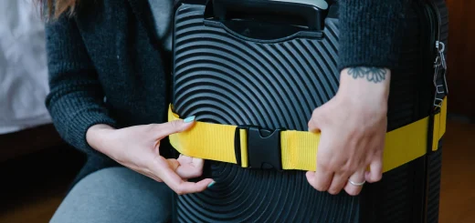 Woman attaching a bright yellow strap to a black ribbed suitcase.